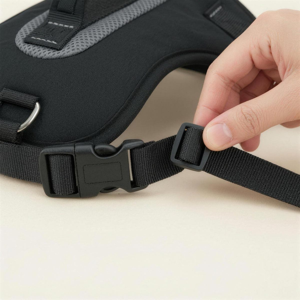 Close-up of a side-release buckle closed on the webbing, and fingers pulling webbing through one of the adjustment sliders.